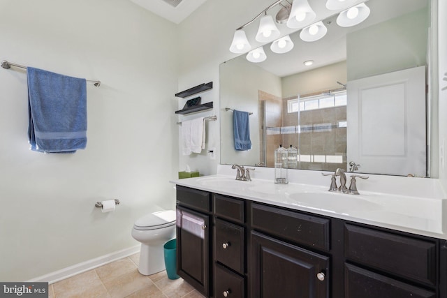 bathroom with toilet, double vanity, a tile shower, and a sink