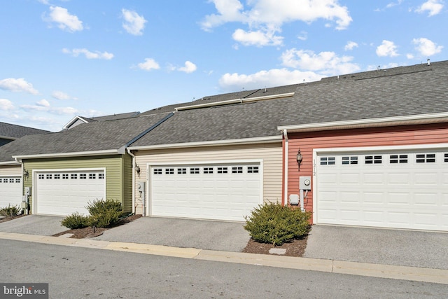 townhome / multi-family property featuring roof with shingles and driveway