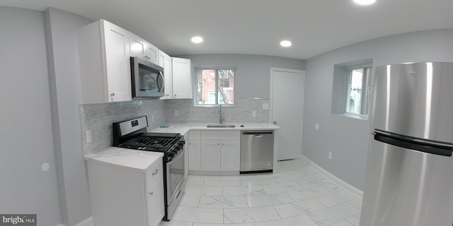 kitchen with tasteful backsplash, sink, white cabinets, and appliances with stainless steel finishes