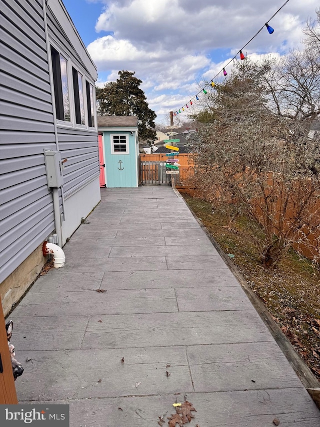 view of patio featuring an outbuilding, a shed, a wooden deck, and fence