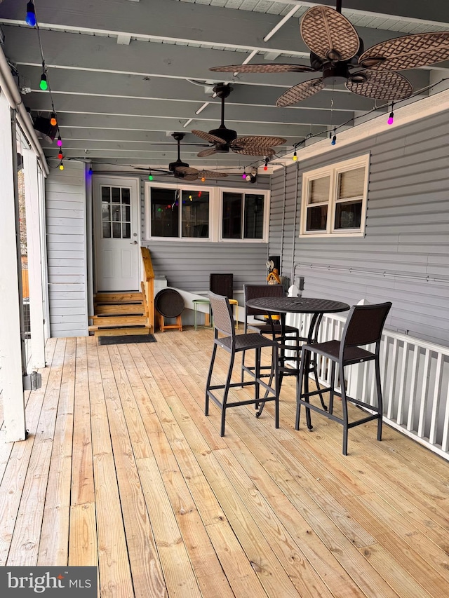 wooden terrace featuring outdoor dining area, ceiling fan, and entry steps