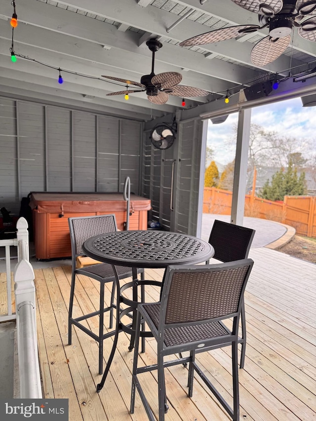 wooden deck with outdoor dining area, fence, a hot tub, and ceiling fan