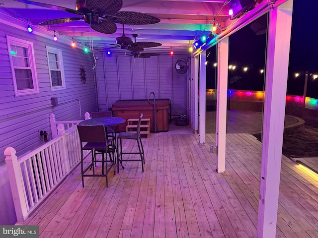 deck at twilight with ceiling fan and a hot tub