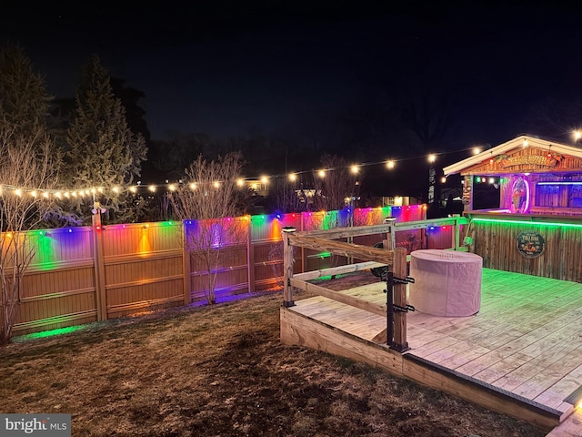 patio at twilight featuring a deck, a pool, and a fenced backyard