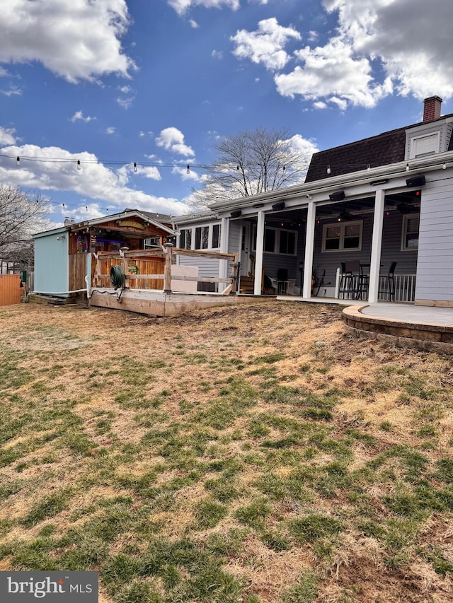 rear view of property featuring a yard, a shingled roof, and a patio area