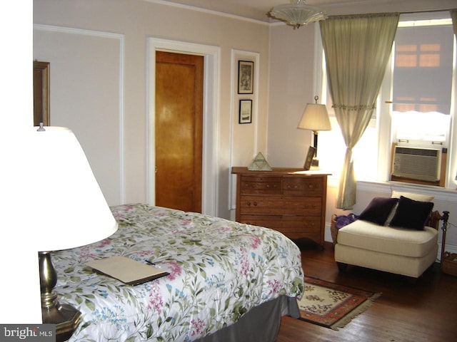 bedroom with crown molding, cooling unit, and dark hardwood / wood-style flooring