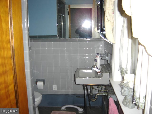 bathroom featuring sink, tile walls, and toilet