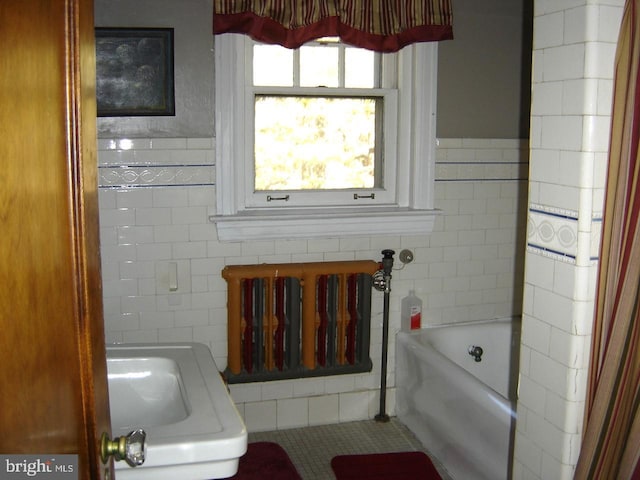 bathroom featuring tile walls, radiator, and a tub