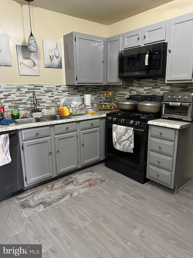 kitchen with gray cabinets, hanging light fixtures, and black appliances