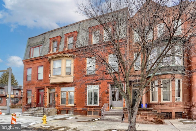 view of property with brick siding and mansard roof