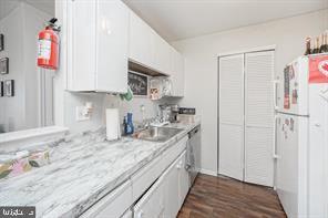 kitchen with white refrigerator, dishwasher, dark wood-type flooring, and white cabinets