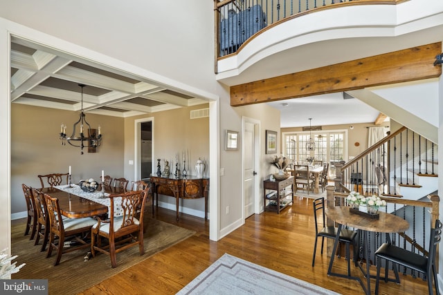 dining area with beamed ceiling, coffered ceiling, dark wood-type flooring, and a chandelier