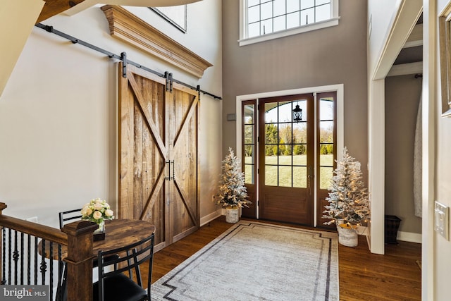 foyer entrance featuring a high ceiling, a barn door, and dark hardwood / wood-style floors