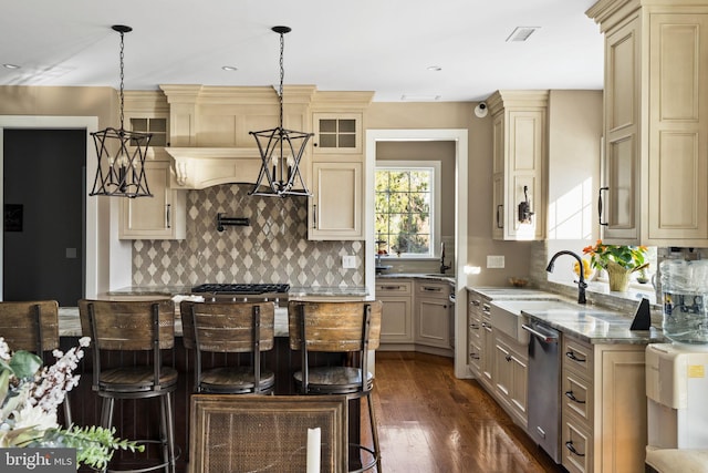 kitchen with a kitchen bar, decorative light fixtures, light stone countertops, and sink