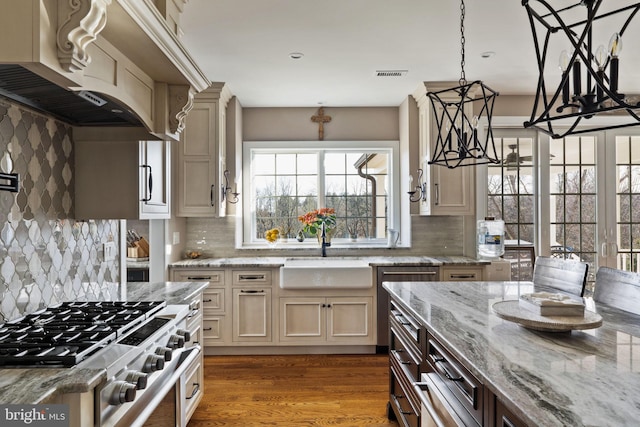 kitchen with cream cabinets, decorative light fixtures, sink, hardwood / wood-style flooring, and light stone countertops