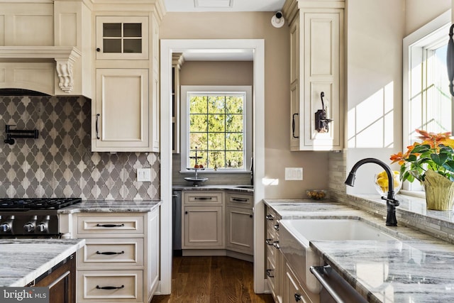 kitchen featuring sink, tasteful backsplash, light stone counters, dark hardwood / wood-style flooring, and cream cabinetry