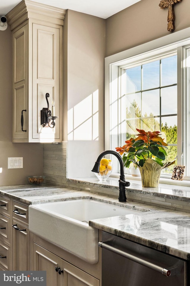 kitchen featuring dishwasher, light stone countertops, and sink