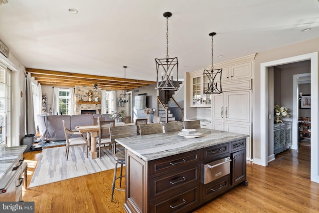 kitchen with dark brown cabinetry, a kitchen island, a breakfast bar area, and light wood-type flooring