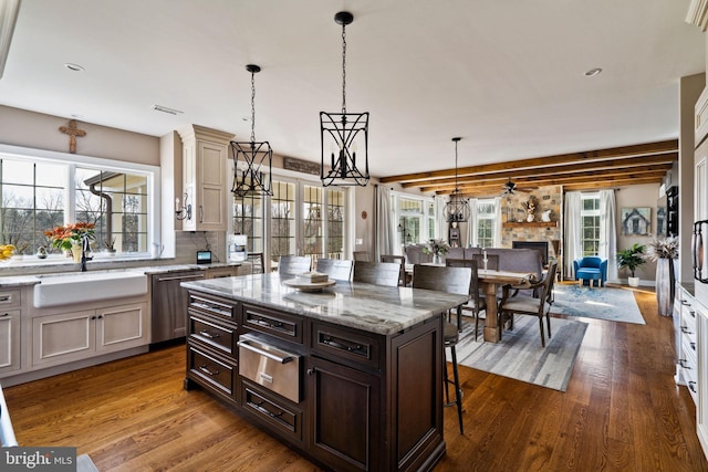 kitchen with dishwasher, sink, a kitchen breakfast bar, hanging light fixtures, and light stone counters