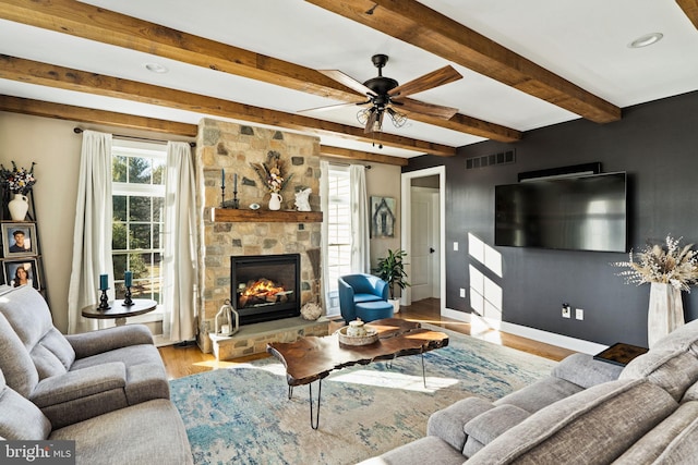 living room with beamed ceiling, ceiling fan, a fireplace, and light hardwood / wood-style floors