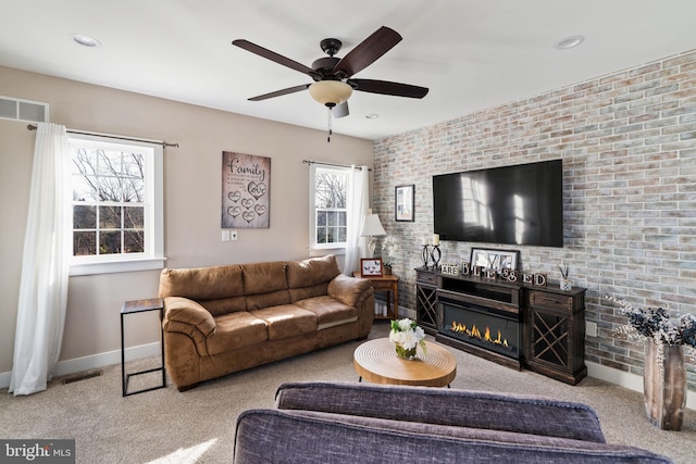 carpeted living room with brick wall and ceiling fan