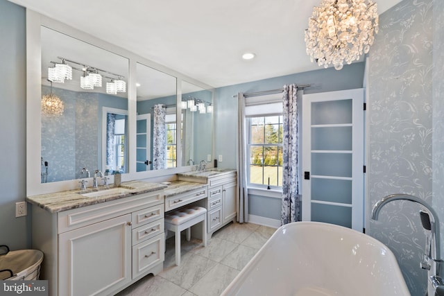 bathroom featuring vanity, a bathtub, and a chandelier