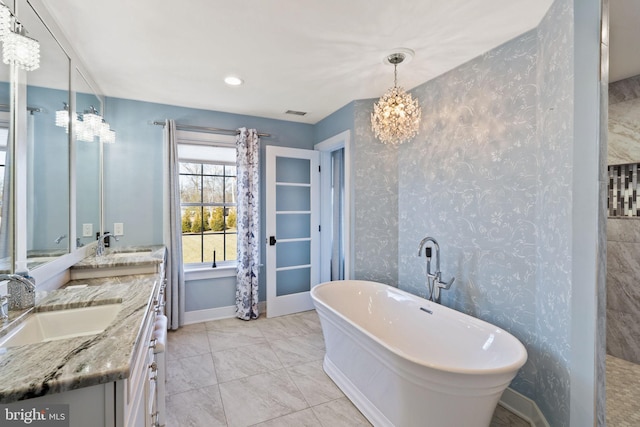 bathroom featuring vanity, tile patterned flooring, a bathtub, and a chandelier