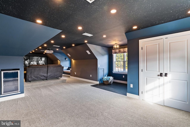 unfurnished bedroom with light colored carpet, lofted ceiling, a closet, and a textured ceiling