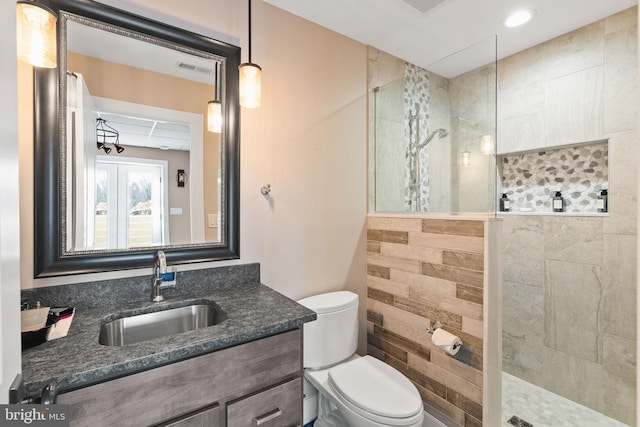 bathroom featuring vanity, toilet, and a tile shower