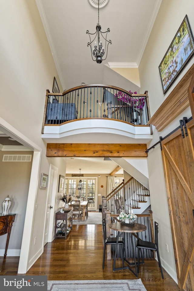 entrance foyer with a high ceiling, crown molding, dark wood-type flooring, and an inviting chandelier