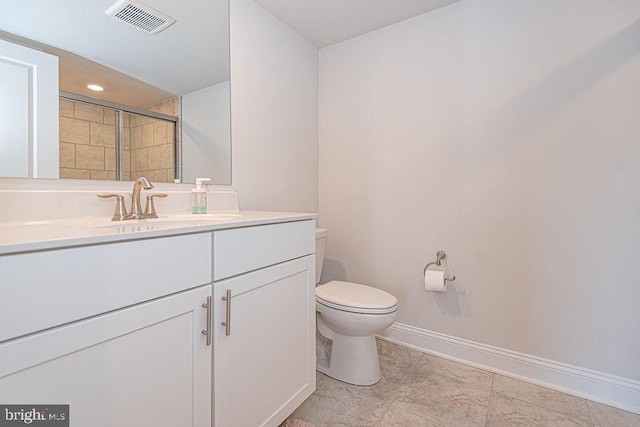 bathroom featuring vanity, toilet, and a shower with shower door