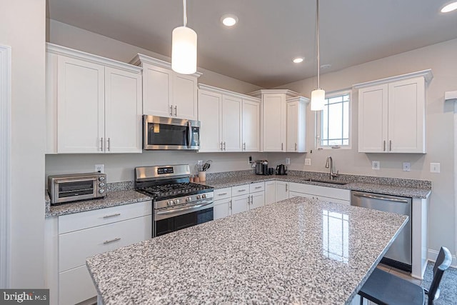 kitchen with stainless steel appliances, white cabinetry, hanging light fixtures, and sink