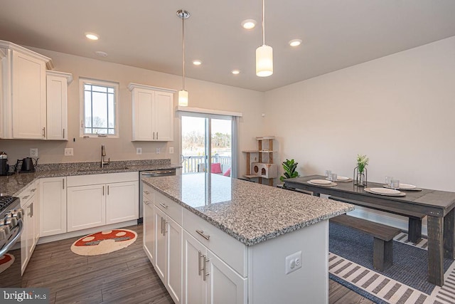 kitchen featuring a kitchen island, sink, pendant lighting, and white cabinets