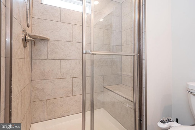 bathroom with a shower with door and toilet