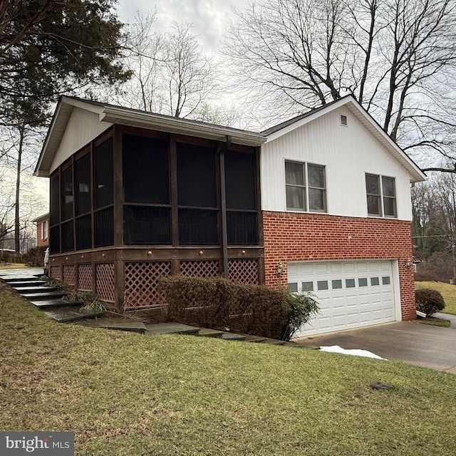 exterior space with a garage, a sunroom, and a lawn