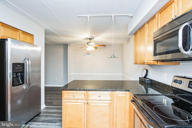 kitchen featuring dark wood-style flooring, a ceiling fan, appliances with stainless steel finishes, dark stone countertops, and track lighting