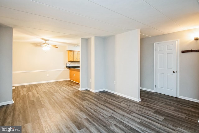 unfurnished living room with baseboards, dark wood finished floors, and a ceiling fan