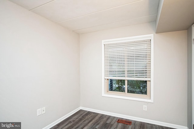 unfurnished room with baseboards, visible vents, and dark wood-type flooring