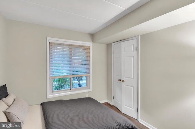 bedroom featuring a closet, baseboards, and wood finished floors