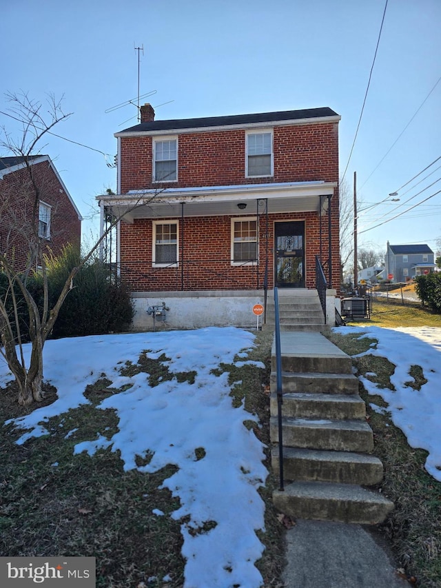 snow covered house featuring covered porch