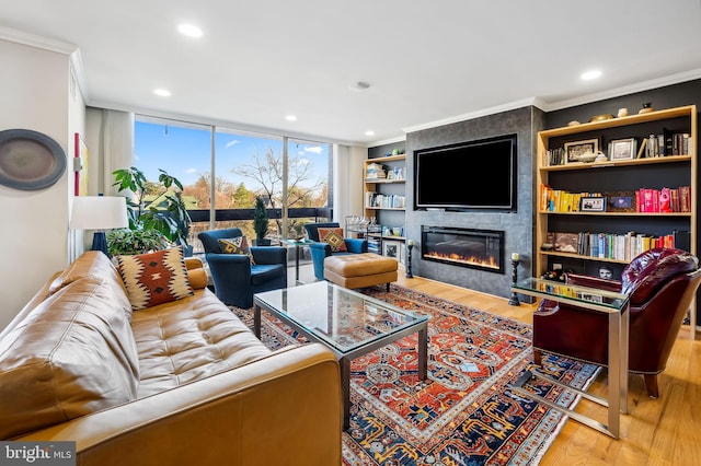 living room with crown molding, built in shelves, a tile fireplace, and hardwood / wood-style flooring