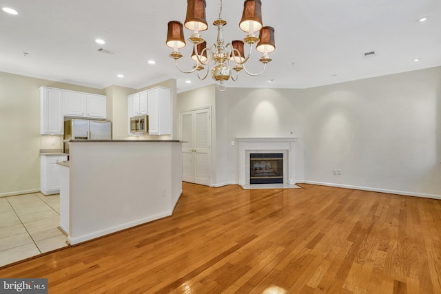 kitchen featuring hanging light fixtures, white cabinetry, appliances with stainless steel finishes, and light hardwood / wood-style floors