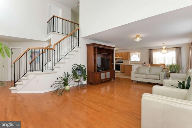 living room with sink, a towering ceiling, and light hardwood / wood-style flooring