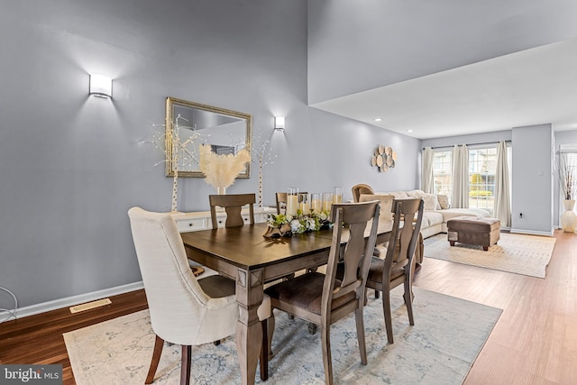 dining area with hardwood / wood-style floors and a high ceiling