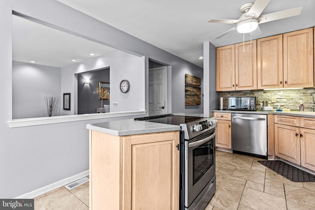 kitchen with light brown cabinets, a kitchen island, ceiling fan, stainless steel appliances, and decorative backsplash