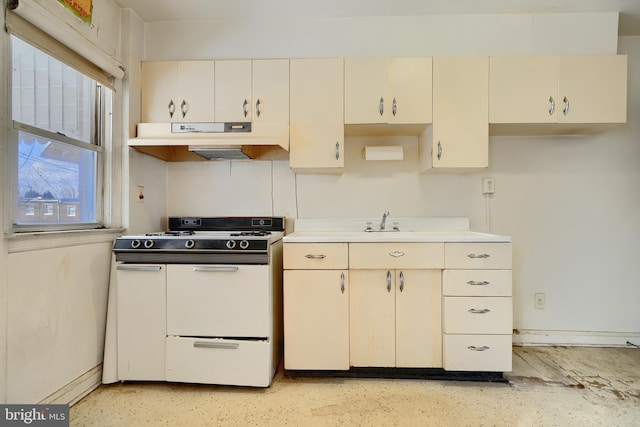 kitchen featuring white gas range, sink, and cream cabinetry