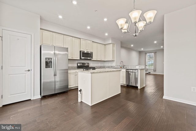 kitchen with appliances with stainless steel finishes, dark hardwood / wood-style floors, kitchen peninsula, pendant lighting, and light stone countertops