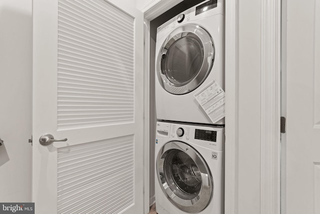 clothes washing area featuring stacked washer and clothes dryer