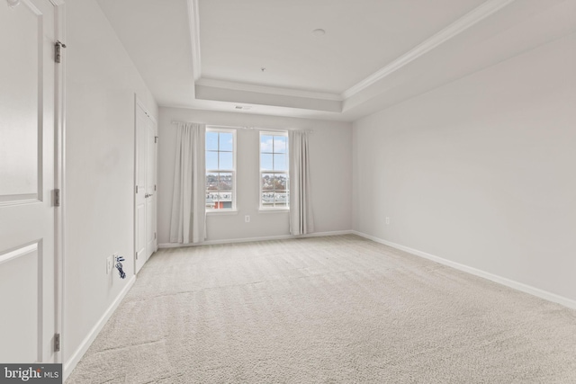 carpeted spare room with a raised ceiling and crown molding