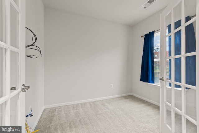 carpeted spare room featuring french doors